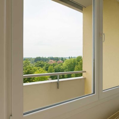 Blick vom Wohnzimmer aus auf den Balkon mit Aussicht auf gruene Landschaft im Studentenwohnheim Hildebrandstrasse Dresden