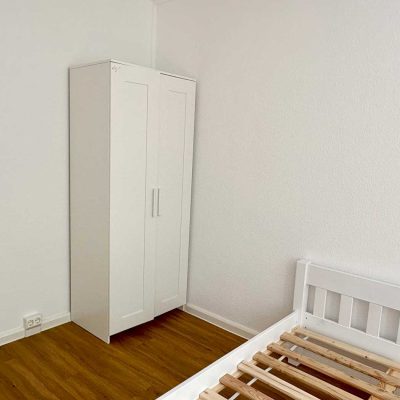 Leeres Schlafzimmer mit weissem Kleiderschrank und Bettgestell im Studentenwohnheim Hildebrandstrasse Dresden