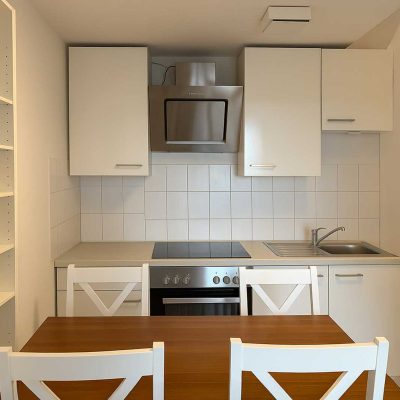 Essbereich mit Holztisch, weißen Stühlen und Küchenzeile im Studentenwohnheim Hildebrandstraße Dresden