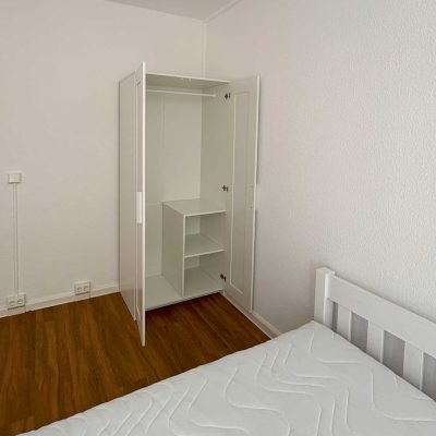 Weißer Kleiderschrank mit offenen Türen und Regal im Zimmer des Studentenwohnheims Hildebrandstraße Dresden